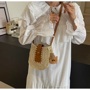 Détail d'un sac bandoulière en paille tissée avec lanière en cuir et breloque ours
