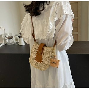 Détail du sac bandoulière en paille avec rabat en cuir brun et breloque chat mignonne