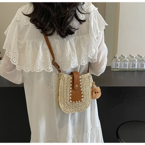 Détail du sac bandoulière en paille avec rabat en cuir marron et breloque pompon