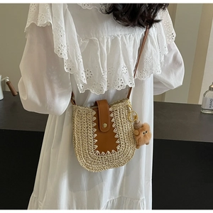 Détail du sac bandoulière en paille tressée avec rabat en cuir brun et breloque ours