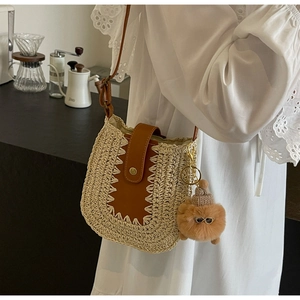 Détail du sac bandoulière en paille avec rabat en cuir brun et pendentif ours en peluche