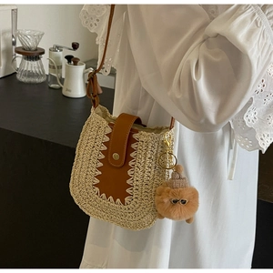 Détail d'un sac bandoulière en paille avec rabat en cuir marron et breloque ours mignon