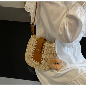 Détail du sac à bandoulière en paille tressée avec fermoir en cuir et breloque chiot mignonne