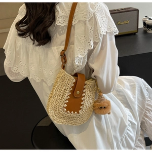 Détail du sac bandoulière en paille tressée avec rabat en cuir brun et breloque