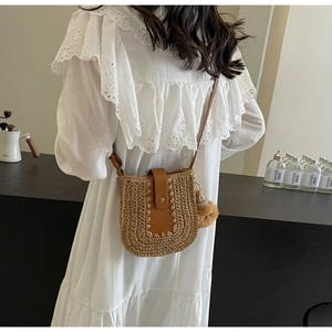 Detailed straw woven bucket bag with brown leather flap and decorative tassel charm