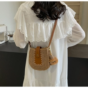 Détail du sac bandoulière en paille avec rabat en cuir et charm boule en peluche