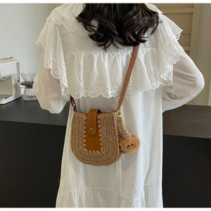 Détail d'un sac en paille tressée avec rabat en cuir et charm peluche mignon