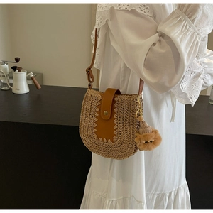 Détail du sac à bandoulière en paille avec garniture en cuir et breloque ours brun