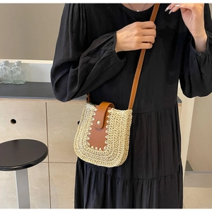 Détail du sac bandoulière en paille avec lanière en cuir marron et fermoir sur modèle