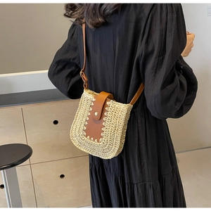 Sac bandoulière en paille avec garniture en cuir brun et surpiqûres blanches sur mannequin