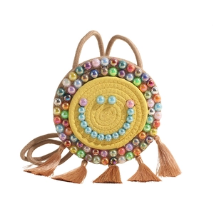 Handwoven yellow round straw shoulder bag with blue beaded smiley face and tassels