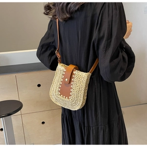 Mannequin portant un sac bandoulière en paille tressée avec détails en cuir marron chic