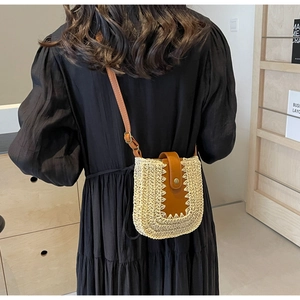 Sac à bandoulière bohème en paille beige avec rabat en cuir marron sur modèle