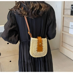 Détail du sac bandoulière en paille tressée avec rabat en cuir brun et sangle réglable