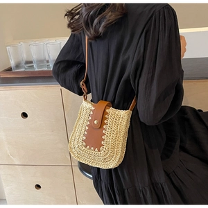 Détail d'un sac bandoulière en paille tressée avec bandoulière en cuir et fermoir en métal