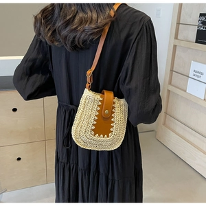 Modèle portant un sac selle en paille tressée avec cuir marron et boucle dorée
