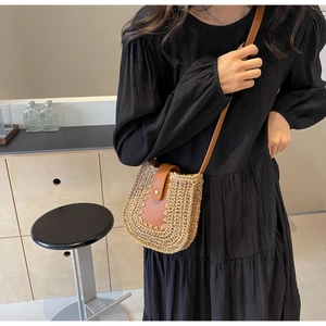 Détail d'un sac en paille tissée avec bandoulière en cuir marron porté par un mannequin