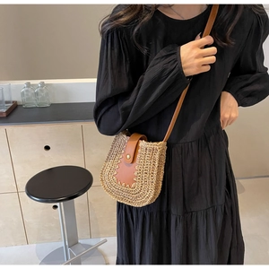 Détail du sac en paille tressée avec rabat en cuir brun et boucle en métal vintage