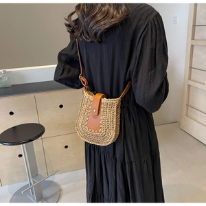 Détail du sac bandoulière en paille tressée avec rabat en cuir marron et boucle métallique