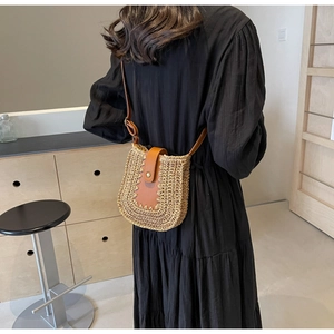 Mannequin portant un sac bandoulière en paille avec bandoulière en cuir et détails rivetés