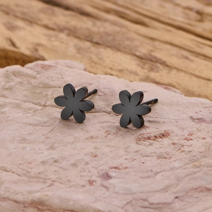 Vue macro de boucles d'oreilles marguerites noir mat sur un support en pierre naturelle
