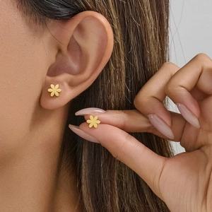 Gros plan d'une femme portant des boucles d'oreilles marguerites dorées en acier inoxydable