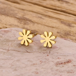 Macro view of gold daisy stud earrings on stone showing petal details and metal texture