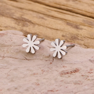 Polished stainless steel daisy stud earrings on natural stone for a minimalist aesthetic