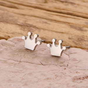 Polished stainless steel crown stud earrings in silver finish on stone texture