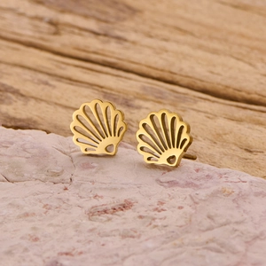 Close-up of gold stainless steel seashell earrings on a pink textured mineral stone
