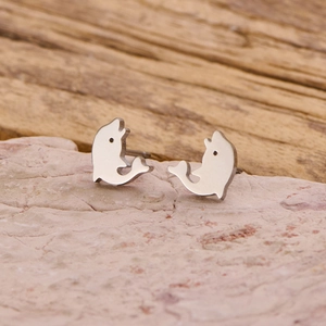 Minimalist silver stainless steel dolphin stud earrings displayed on natural stone