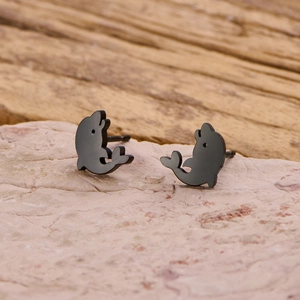 Detailed macro shot of cute black dolphin stud earrings on a natural stone surface