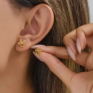 Gold-toned ILY hand sign stainless steel studs worn by a model in a minimalist style