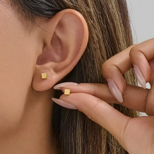 Minimalist 4mm gold square stud earrings with matte finish shown on model ear