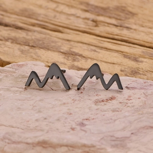 Gros plan de boucles d'oreilles sommets de montagne en finition noir mat sur pierre