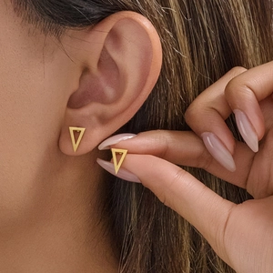 Boucles d'oreilles triangle creux dorées au style géométrique moderne sur mannequin