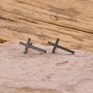 Detail of matte black stainless steel cross earrings on a natural stone base