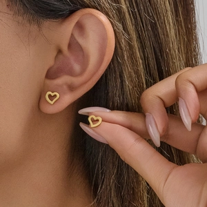 Boucles d'oreilles cœur dorées avec découpe minimaliste portées par un mannequin de près