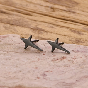 Detail shot of minimalist black matte star stud earrings on a natural stone base