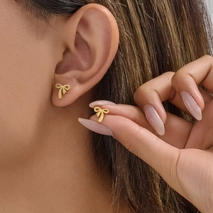 Minimalist gold butterfly stud earrings for women shown worn on ear and hand details