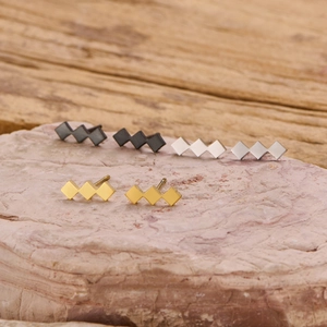 Three pairs of geometric quadrilateral stud earrings in black, silver, and gold steel