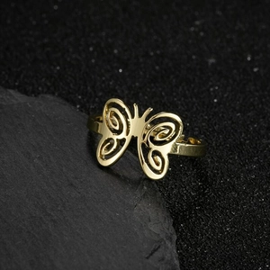 Bague papillon dorée élégante avec ailes en spirale ajourées sur fond noir texturé