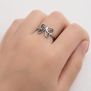 Gros plan d'une bague argentée ouverte avec un motif de papillon ajouré sur l'index