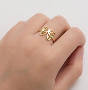 Gros plan détaillé d'une bague papillon dorée avec motifs ajourés portés à la main