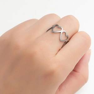 Close-up of geometric hollow heart patterns on a polished stainless steel band ring