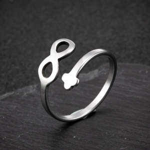 Minimalist stainless steel infinity and cross open ring on dark stone background