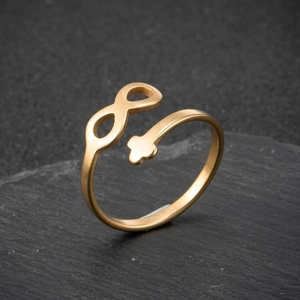 Minimalist gold infinity cross open ring with a matte finish on stone background