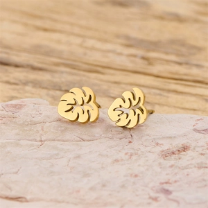 Detailed close-up of 18K gold-plated leaf studs on a textured stone surface