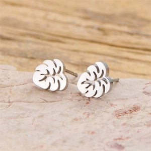 Minimalist stainless steel monstera leaf stud earrings with hollow design on stone surface