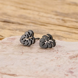 Detail of leaf-shaped earrings in matte black finish on a natural stone surface
